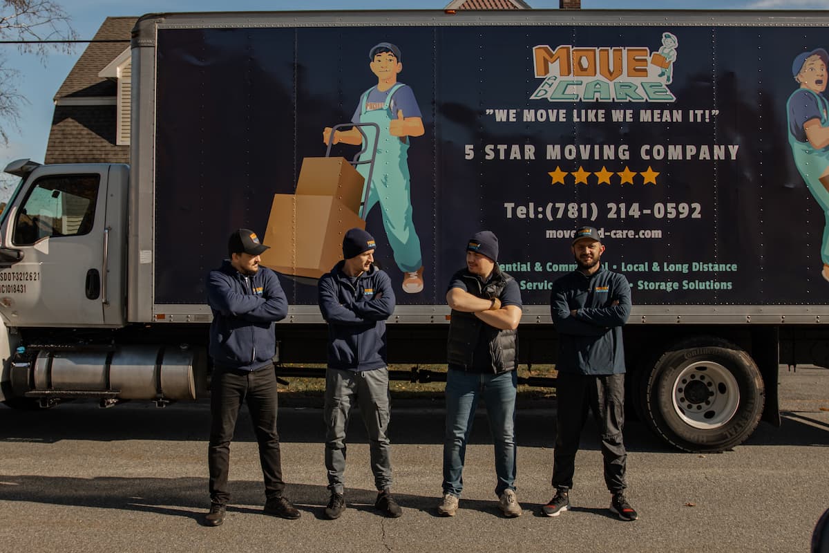 Four Move and Care movers lined up in front of a branded moving truck