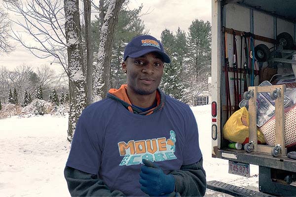 Move and Care mover next to a loaded moving truck on a snowy day